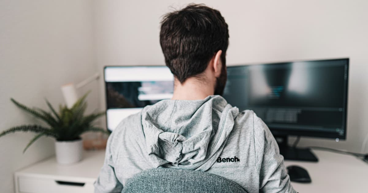 Someone working at a two-monitor desk set up at home